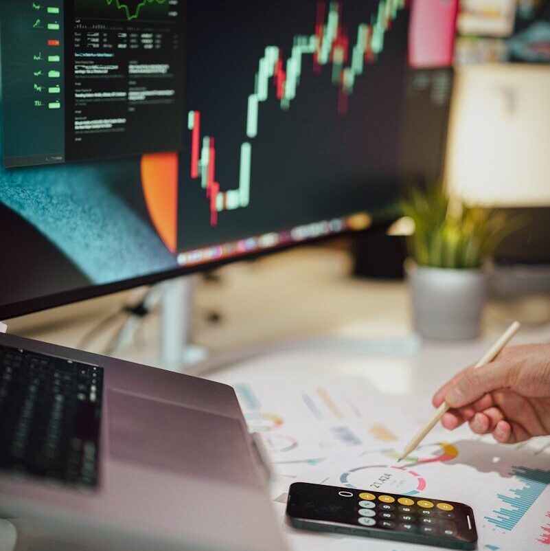 a person writing on a piece of paper next to a computer monitor