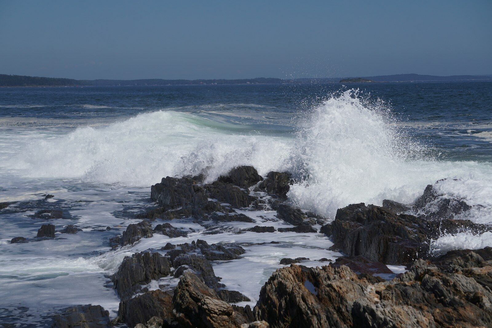 Waves crashing against rocky shore under the clear sky